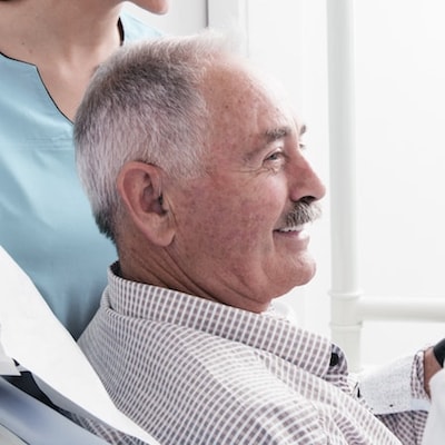 Older male patient sat in the dentist chair and smiling